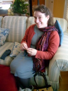 Christine Guest sitting on the couch knitting a glove at her Mom's house